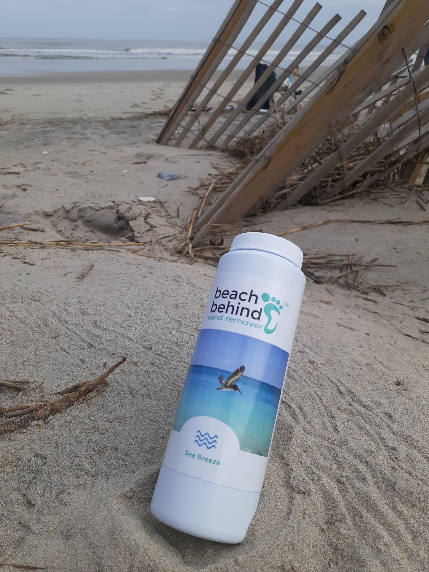 beach sand bottle of sand remover with beach picket fence and ocean in background